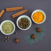 Flat lay of assorted spices including cinnamon, turmeric, and star anise on a dark surface.